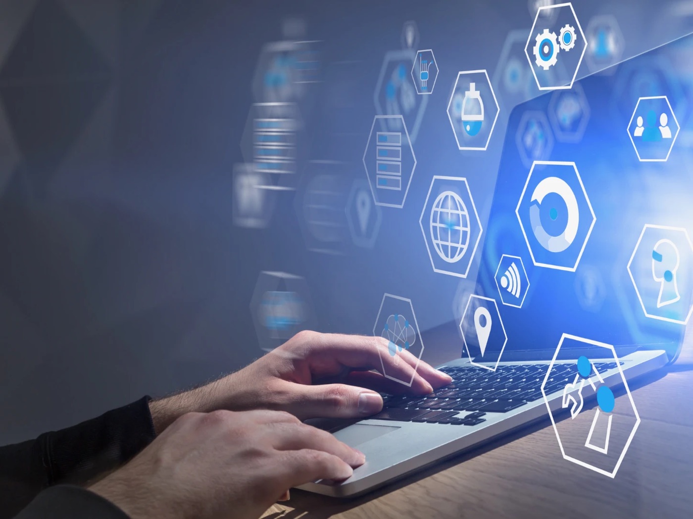 Hands typing on a laptop with floating hexagon icons for tools, people and settings